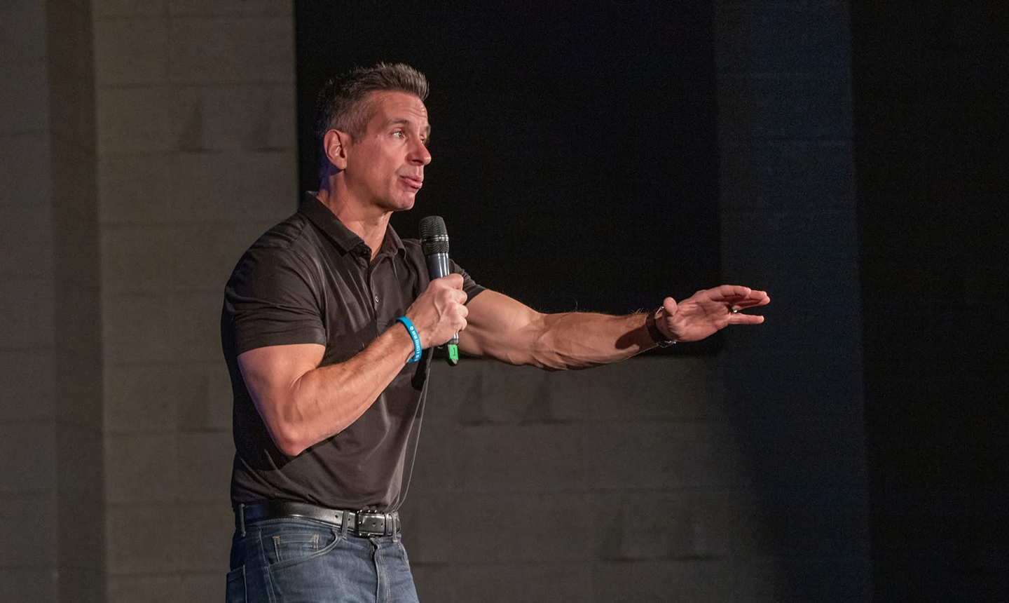 Damon West speaking on stage with a microphone
